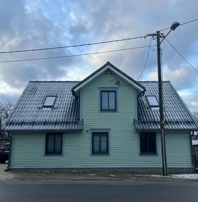 Rohelise puidust fassaadi ja metallist katusega maja tehtud tööde hulgas, et näidata värvimistööde tulemust